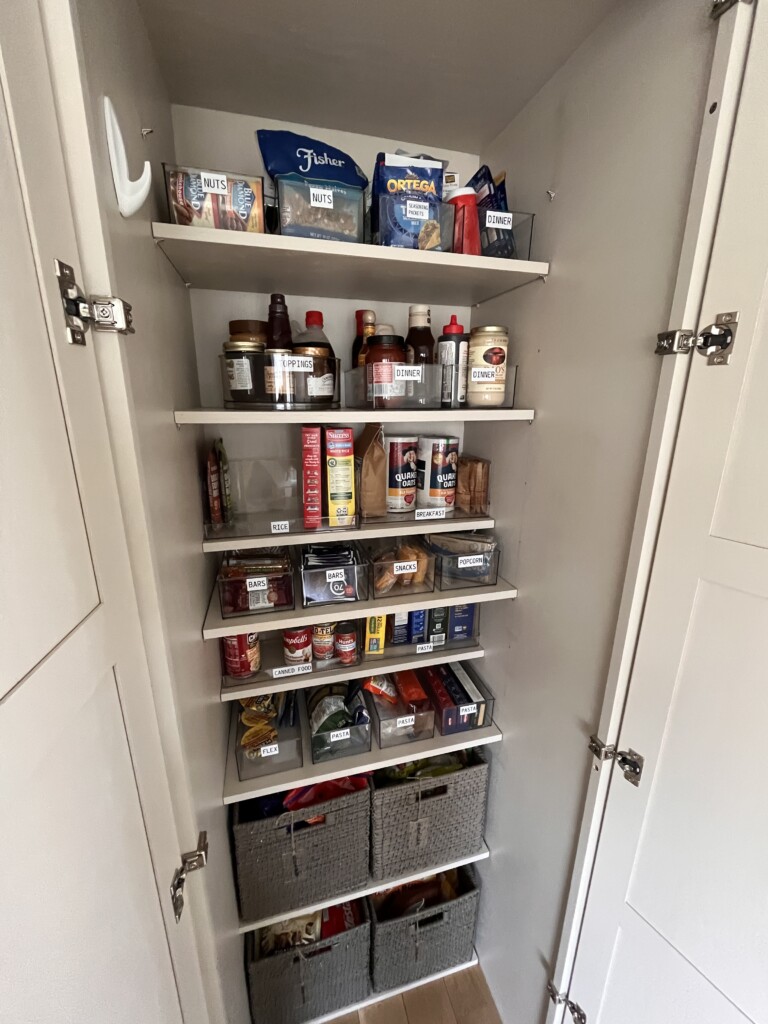 an organized pantry with clear bins, white labels with black font
